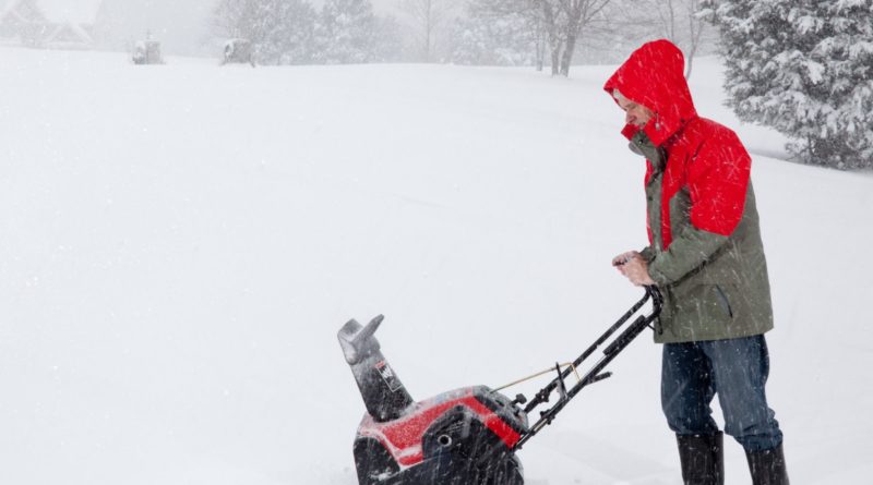 1592717 man using snow blower on snowy drive