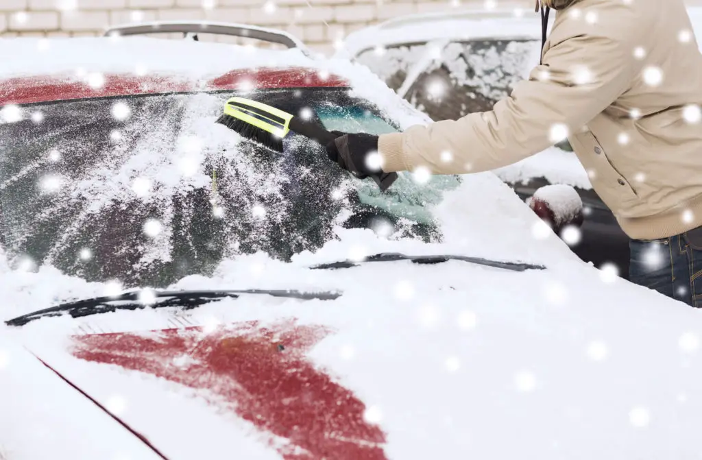 man cleaning snow from car